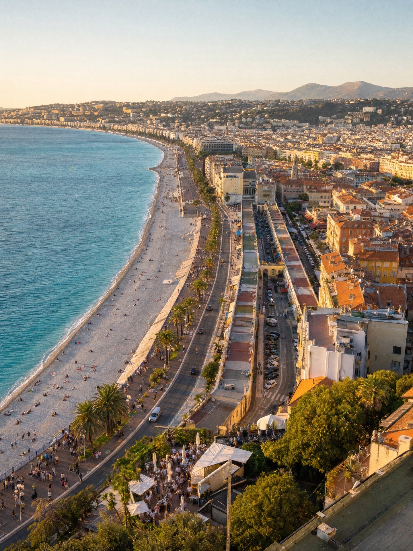 La Promenade des Anglais et la baie des Anges en fin de journée, vues d'en haut — plage et terrasses animées.