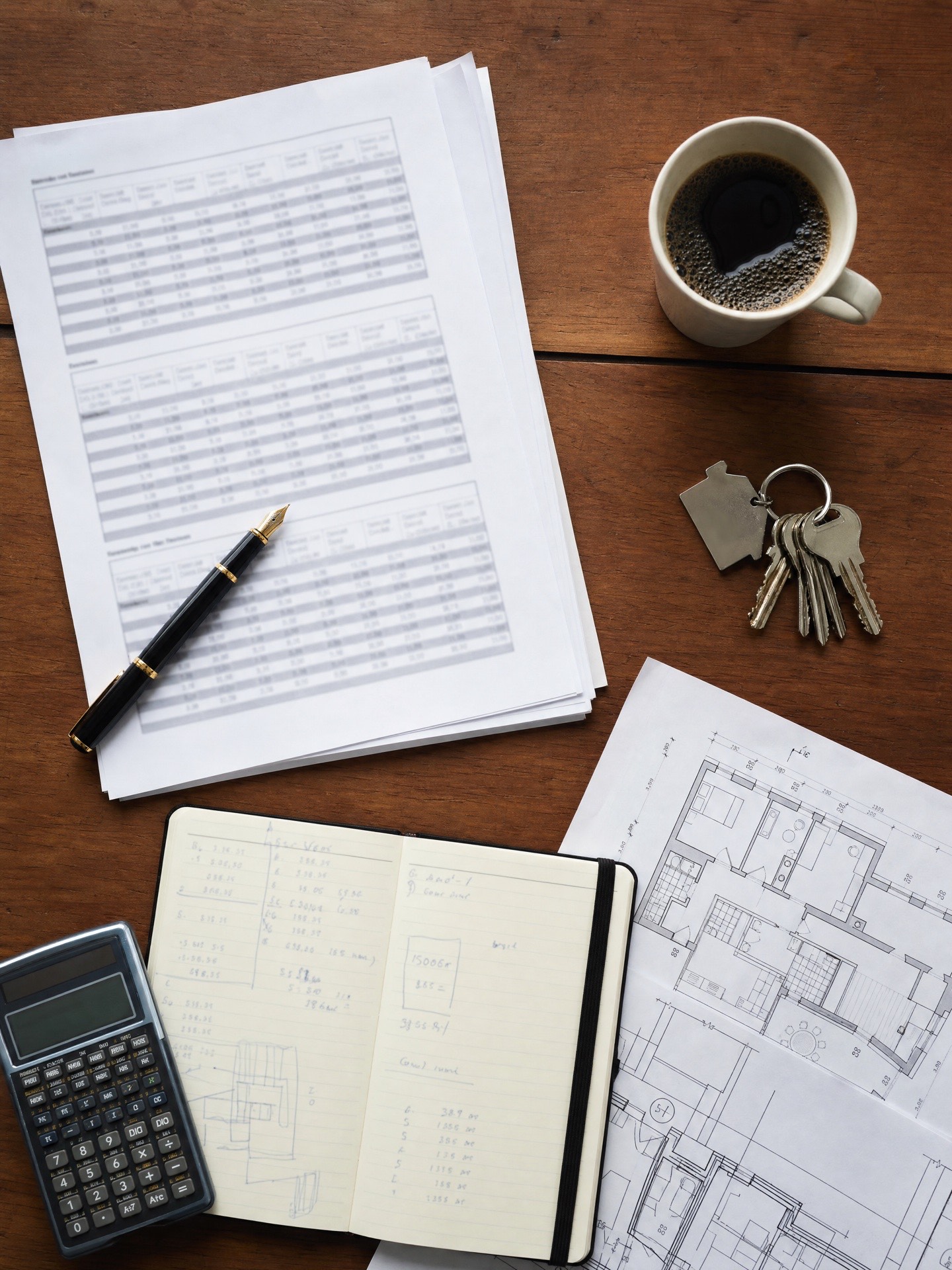 Vu de dessus : l'avis de valeur posé sur le bureau, avec plan d'appartement, calculatrice, carnet et trousseau de clés.